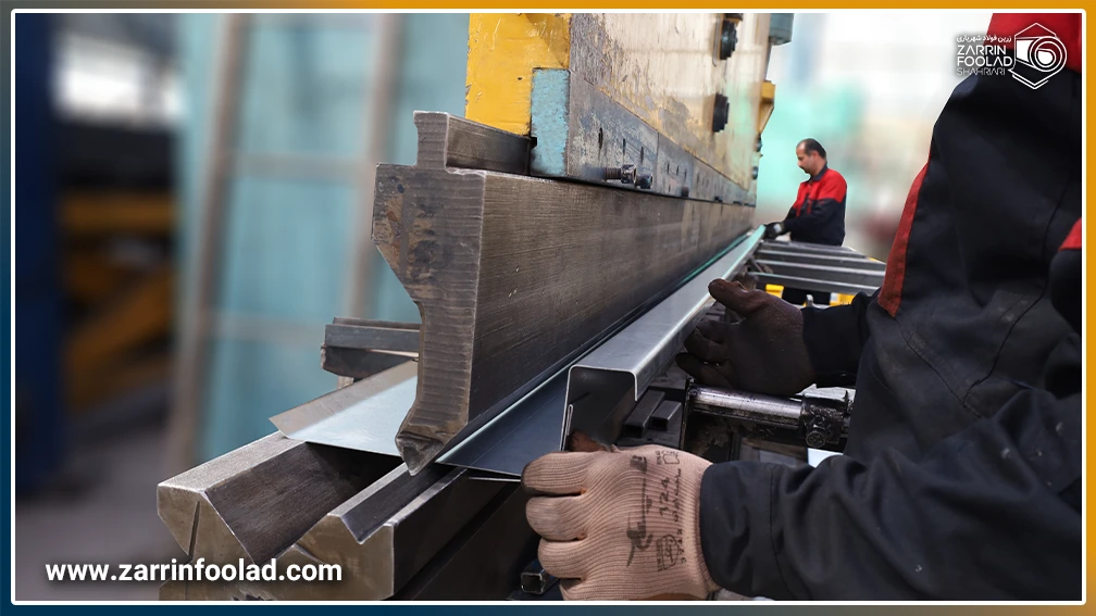 دستهای اپراتور در حال قرار دادن قطعه فلزی زیر دستگاه پرس برک