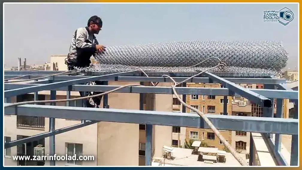 در تصویر یک مرد بر روی سقف در حال نصب توری مرغی فلزی است