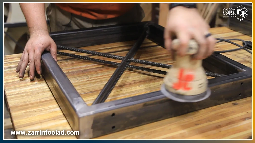 یک مرد در حال سنباده زدن محلهای جوشکاری پروفیلهای جوش داده شده به هم