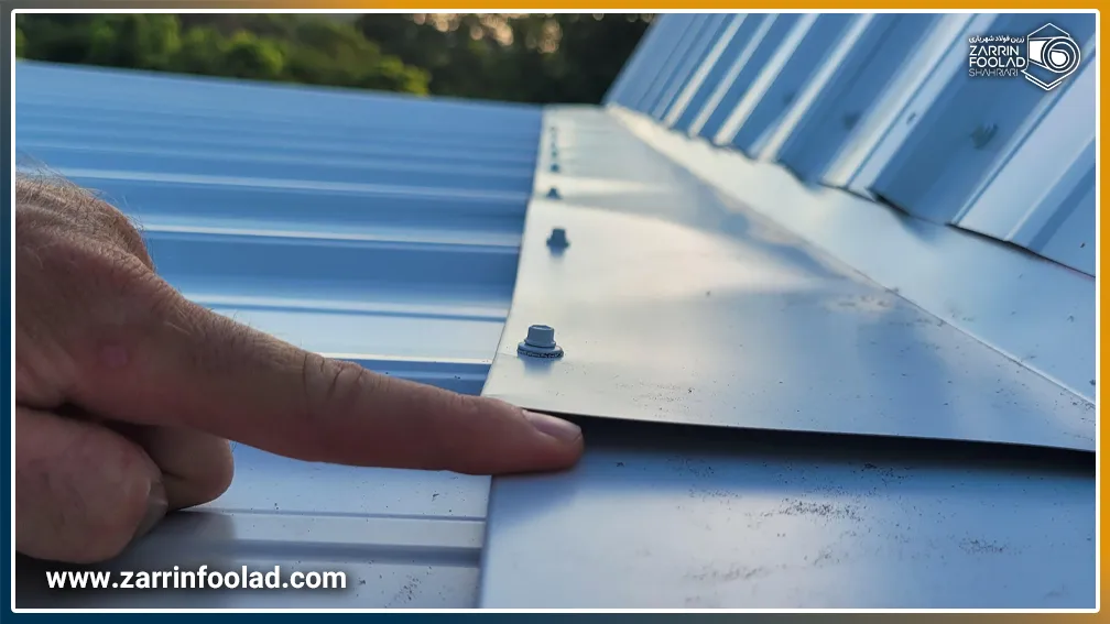 ورق سقف گالوانیزه که انگشت یک فرد در زیر آن قرار دارد.
