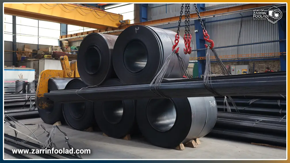 رول‌های سیاه فولادی در بک گراند تصویر و چند شخه پروفیل آبرو در حال بارگیری با جرثقیل