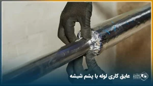 دست شخص در حال عایق کردن لوله فلزی با پشم شیشه